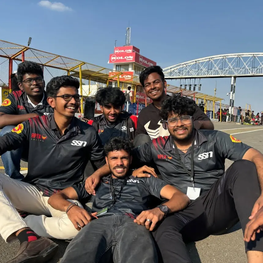 Part of the crew sitting together at the circuit in team shirts.
